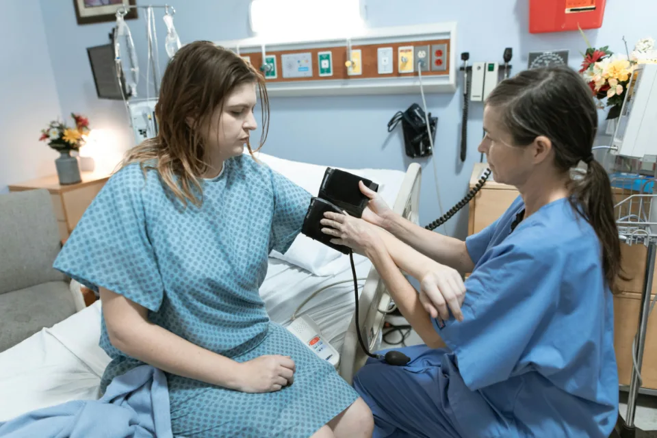 Eine Krankenpflegerin legt einer Patientin im Krankenhaus ein Blutdruck-Gerät an.