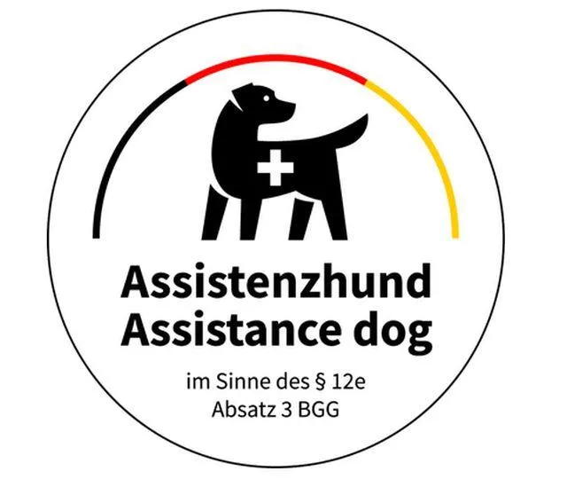 offizielles Abzeichen für Assistenzhunde: schwarz-rot-goldener Bogen, im Bogen befindet sich ein Hundepiktogramm mit einem Kreuz auf dem Rücken. Darunter steht: "Assistenzhund Assistance Dog im Sinne des §12e Absatz 3 BGG"